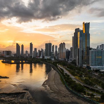 Sunset over a modern city skyline with reflective skyscrapers and a river.