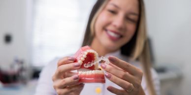 Woman holding a dental mold and clear aligner.