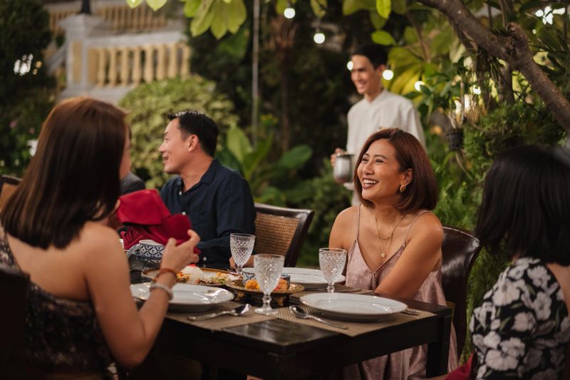 Family members enjoying a relaxed outdoor dinner together, smiling and talking.