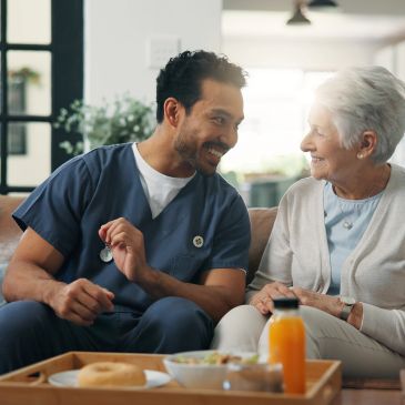 Caregiver sharing a joyful moment with elderly woman at home.