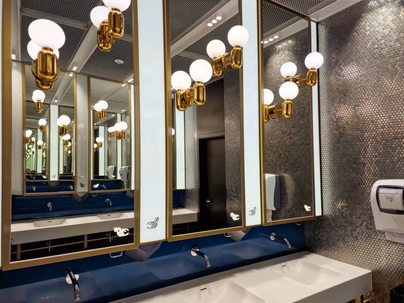 Gdansk, Poland  02-13-2023: This restroom showcases a chic design with decorative mirrors, gold accents and modern lighting