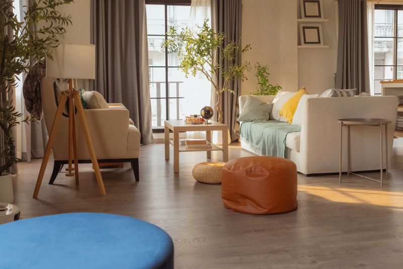 Cozy modern living room interior with comfortable armchairs and coffee table near bright window, natural sunlight and houseplants creating warm minimalist home decor, elegant apartment lifestyle space.