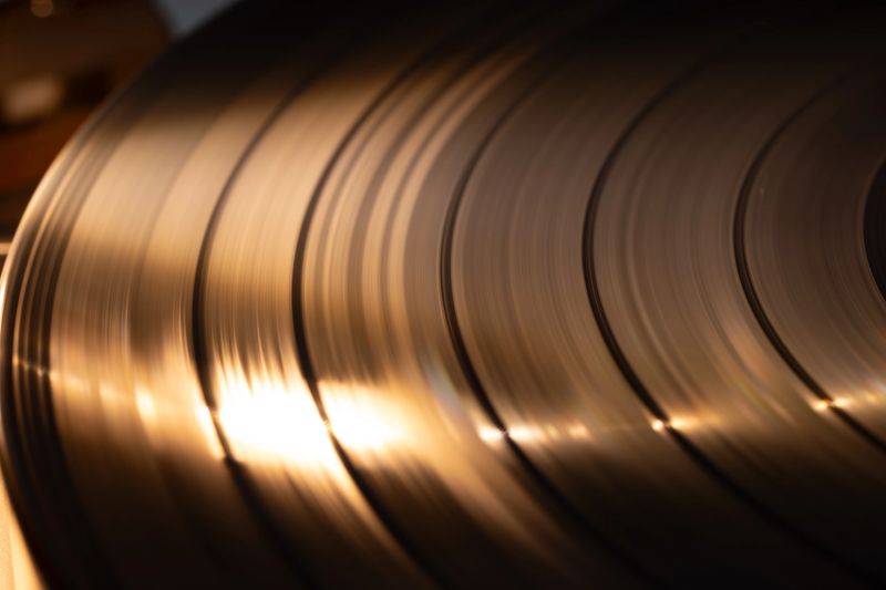 Close-up of vintage vinyl records highlighting grooves and reflections, with soft lighting enhancing the texture and detail of the records