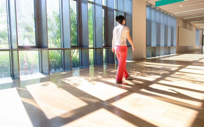 Woman walking through the corridor with shadow on the floor