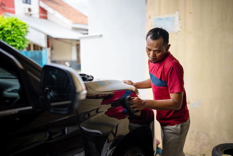 A professional auto detailer uses an electric polishing machine to buff and polish the surface of a car door. The image captures the car detailing process, highlighting vehicle maintenance, surface polishing, and professional automotive care. Professional car detailer and rotary polisher machine