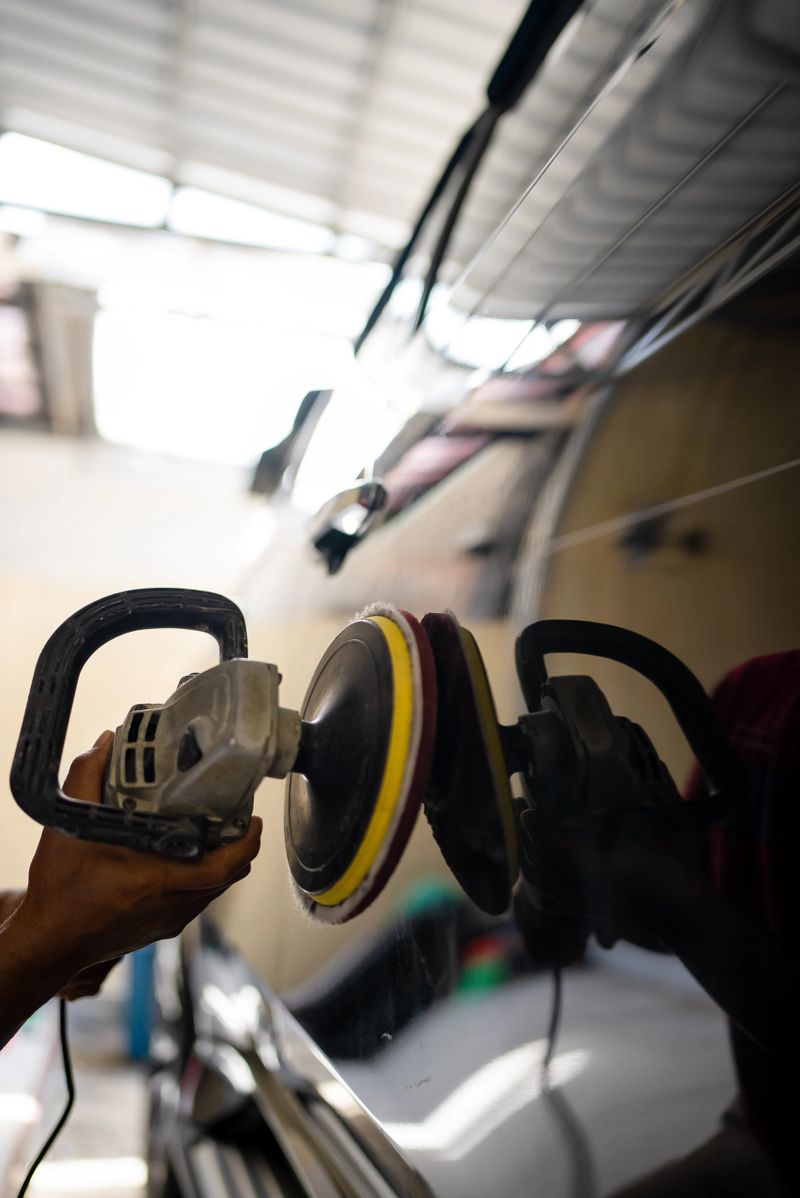 A professional auto detailer uses an electric polishing machine to buff and polish the surface of a car door. The image captures the car detailing process, highlighting vehicle maintenance, surface polishing, and professional automotive care. Professional car detailer and rotary polisher machine