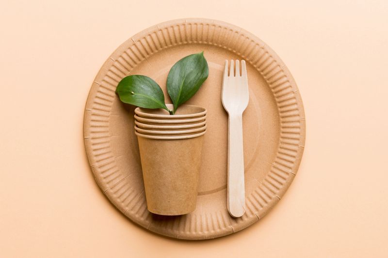 set of empty reusable disposable eco-friendly plates, cups, utensils on light white colored table background. top view. Biodegradable craft dishes. Recycling concept. Close-up.