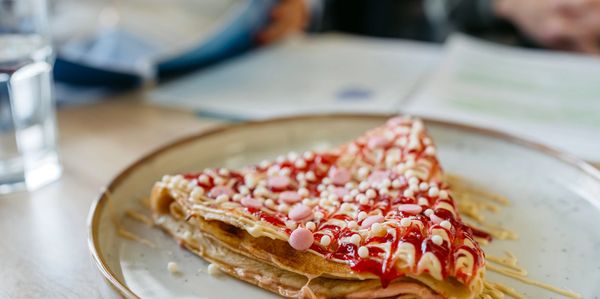 Croissant topped with strawberries and chocolate drizzle on a wooden board.