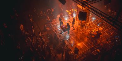 Band performing on a lit stage with an audience.