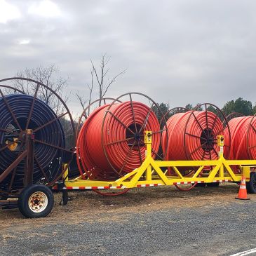 Large reels of industrial hoses on a yellow trailer.
