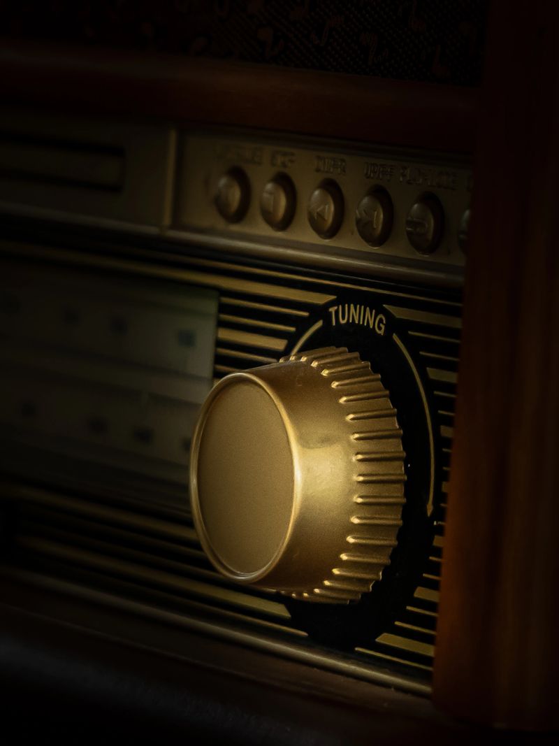 Close-up of a vintage radio tuning knob with warm, soft lighting and shallow depth of field. The image highlights retro design, textured materials, and a nostalgic atmosphere, ideal for themes like music, technology history, and analog lifestyle.