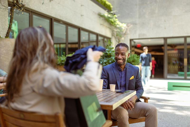 Business colleagues enjoying a casual conversation at an outdoor café. 5th Ave, Manhattan, NYC
