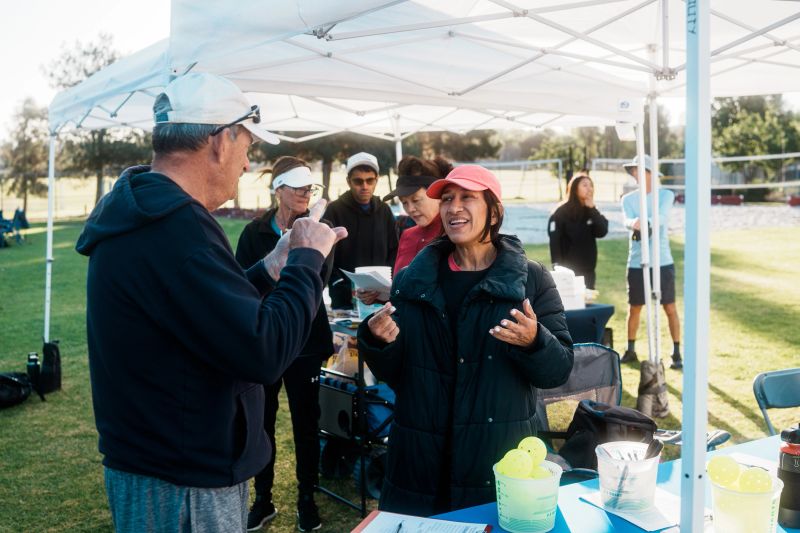 A volunteer chats with an athlete using ASL while they are registering during a pickleball tournament.