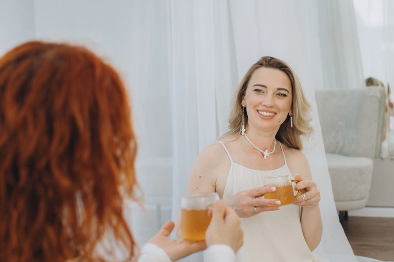 Two women connecting, drinking herbal tea during a theta healing session focused on well-being, spiritual practice, and positive energy