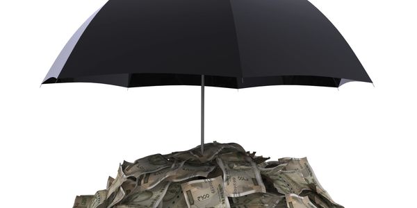 Black umbrella protecting pile of Indian currency notes.