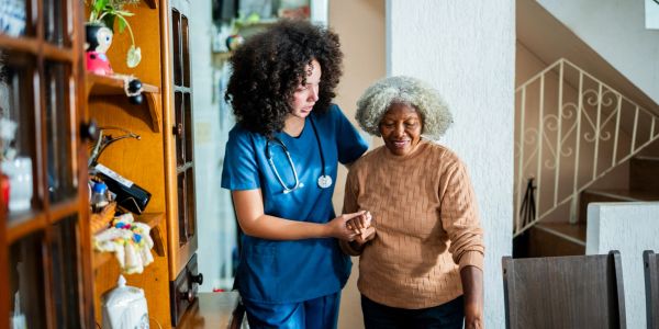 Nurse assisting elderly woman with walking.