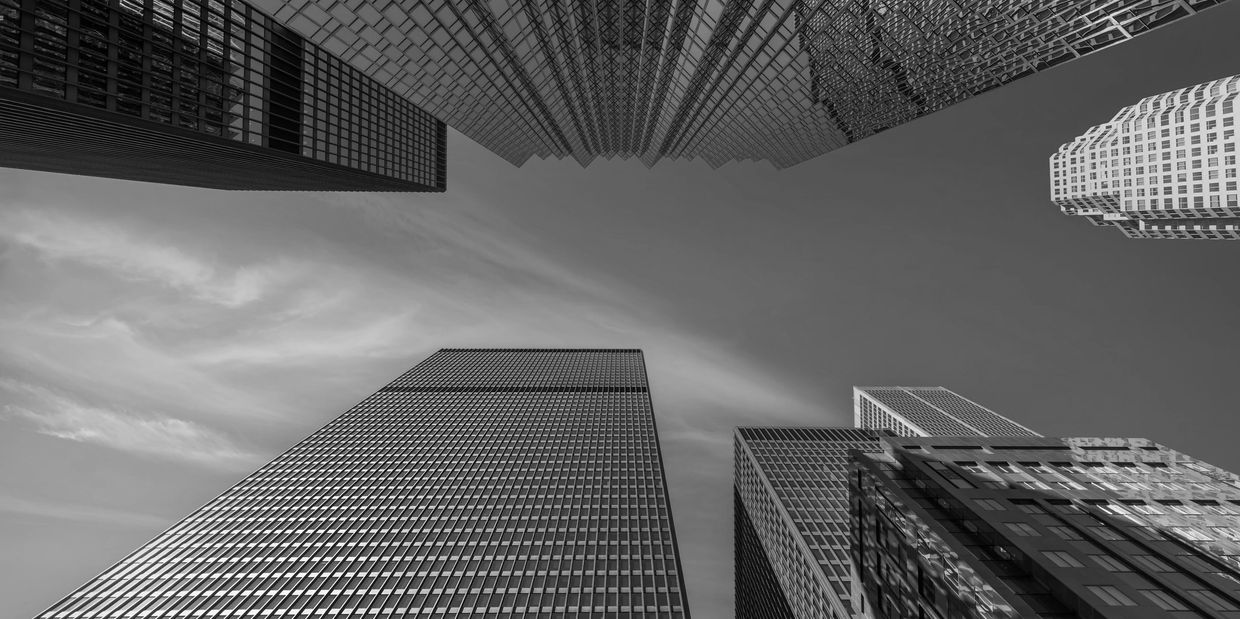 Black and white photo of skyscrapers from ground view.