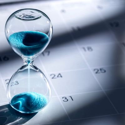 Hourglass with blue sand on a calendar.
