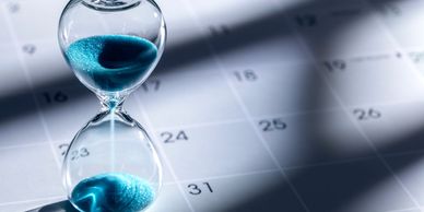 Blue hourglass on a calendar representing coordinated deadlines and time-sensitive services