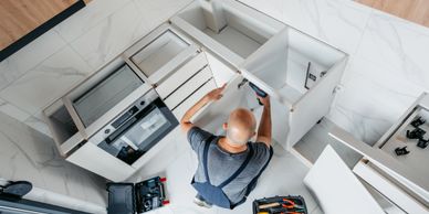 A man installs kitchen cabinets from an overhead view.