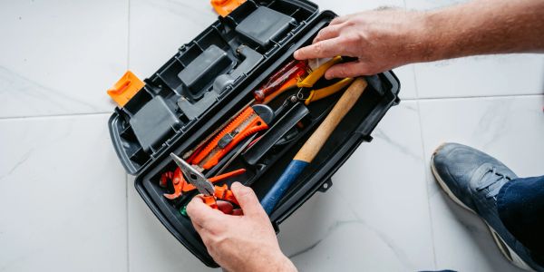 Person organizing tools in a box on the floor.