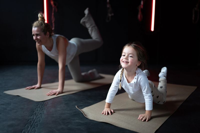 Mother and daughter smiling while exercising on yoga mats, promoting healthy family lifestyle and fitness.