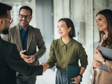 Business professionals shaking hands in a modern office.