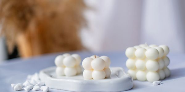 White bubble candles in cube shapes on a white tray and table.