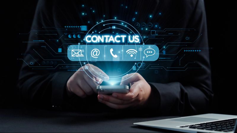 Close-up of hands holding a smartphone with illuminated contact icons, symbolizing modern communication methods for businesses and individuals in a digital world. Qubit