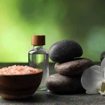 Spa items with stones, salt, and oil bottle.