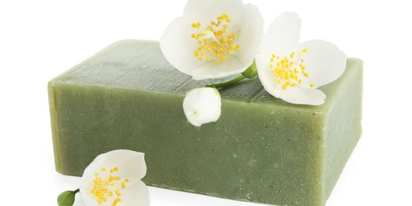 Green soap bar with white jasmine flowers on top.