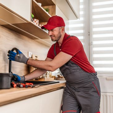 Plumber fixing a kitchen sink with tools on the counter.