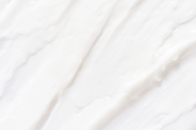 Smooth white cream texture background with subtle waves for skincare or cosmetic product design.