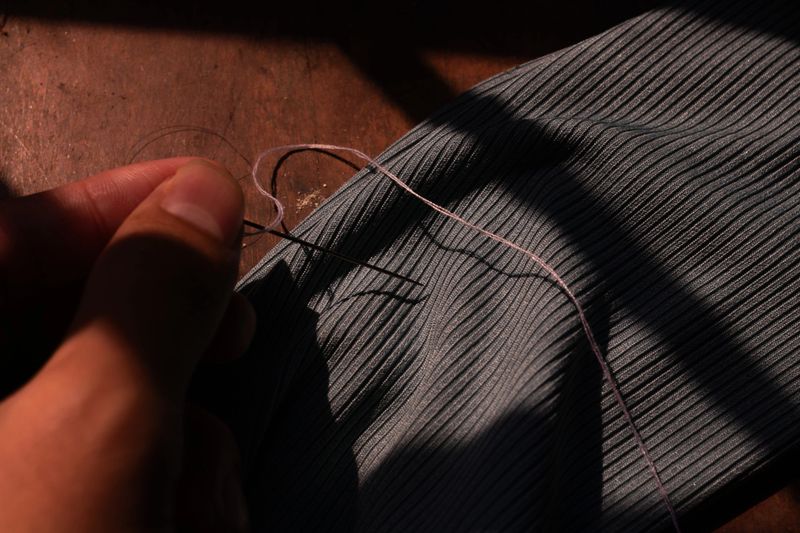 A detailed photo showing the manual process of mending clothes, emphasizing traditional craftsmanship and sustainability