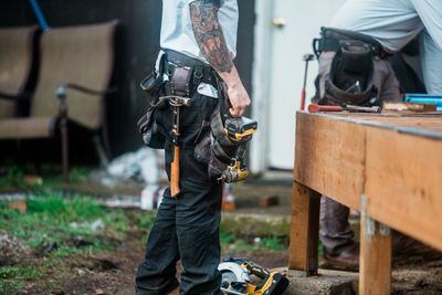 Construction worker holding power drill outdoors.