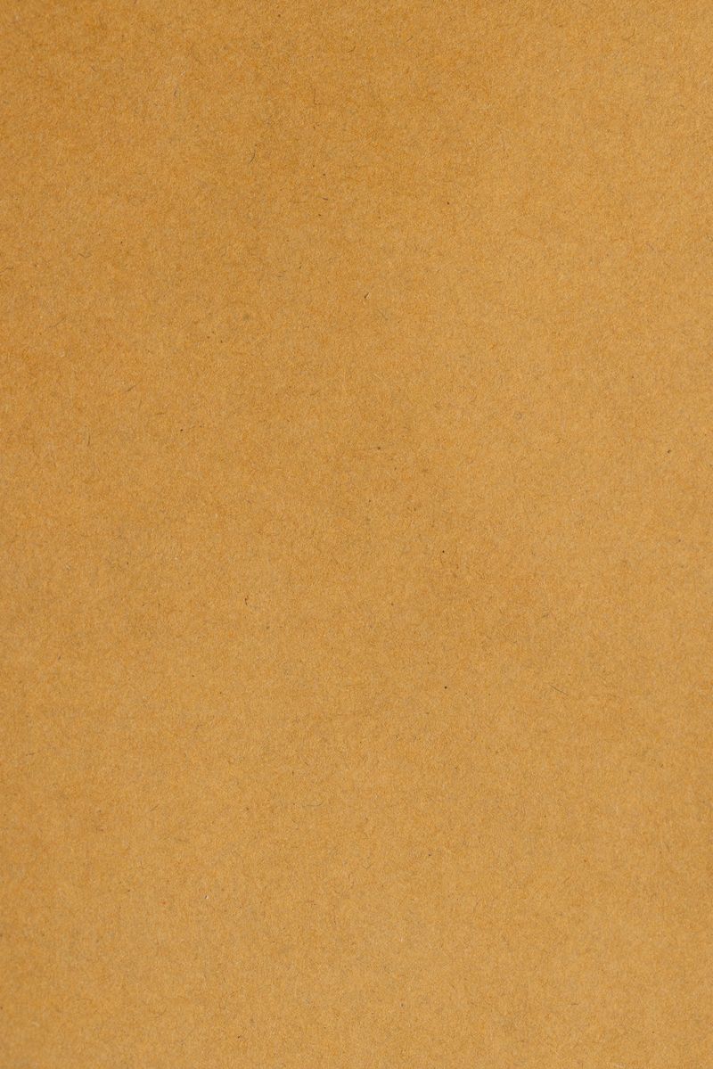 High-resolution macro shot of natural brown kraft paper texture. Recycled paper background with visible fibers and organic grain, ideal for eco-friendly designs, scrapbooking, and vintage-themed projects.