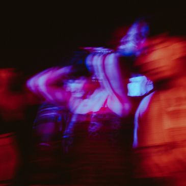 Blurry neon-lit people dancing.