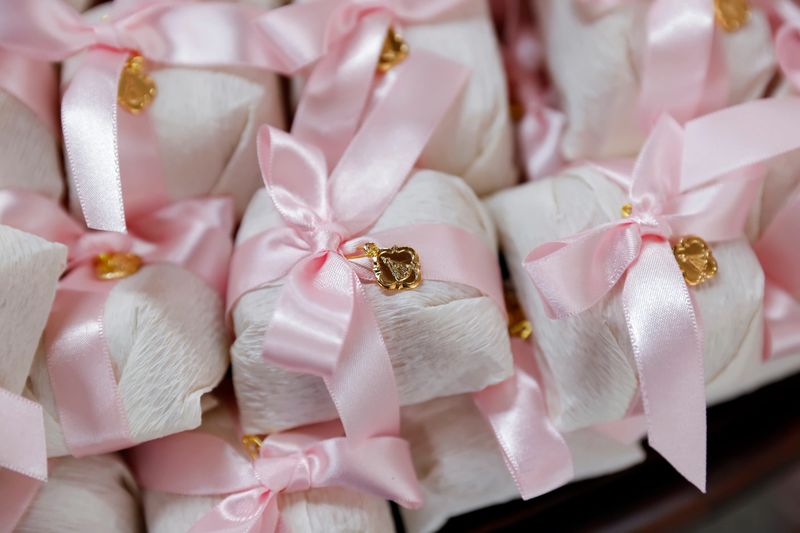 Fine wedding favors wrapped in white crepe paper with pink satin ribbons and gold decorative pendants. Perfect for bridal showers, baptisms, and elegant party favors