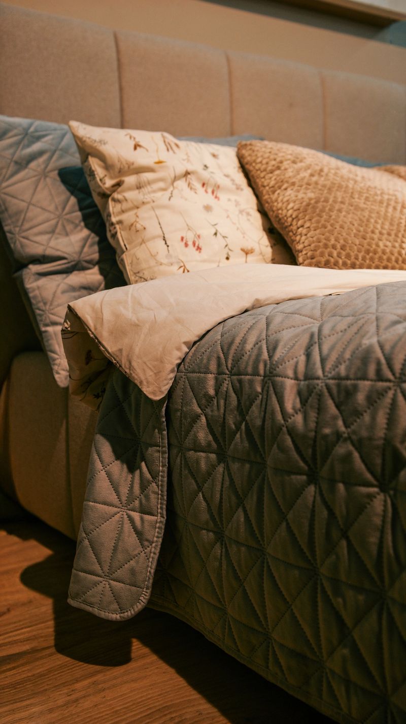 A close-up view of a comfortable bed with plush pillows and a textured quilt, suggesting relaxation and warmth
