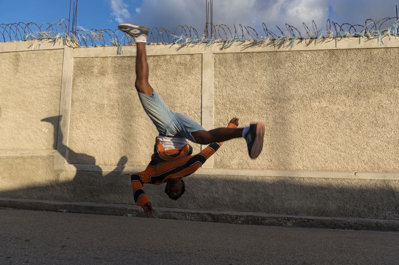 A young man dancing in the street in an urban setting. The image highlights movement, artistic expression, and the energy of youth in public spaces.