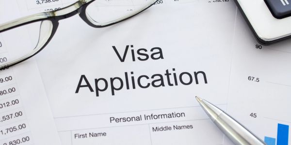 Close-up of a visa application form with a pen and eyeglasses.