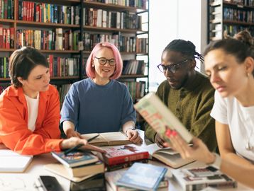 Group of young adults studying together in a library.
