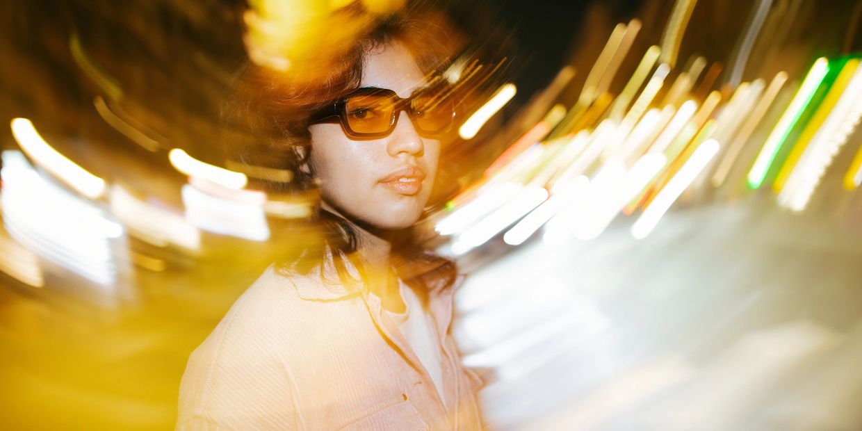 Woman with sunglasses surrounded by swirling lights.