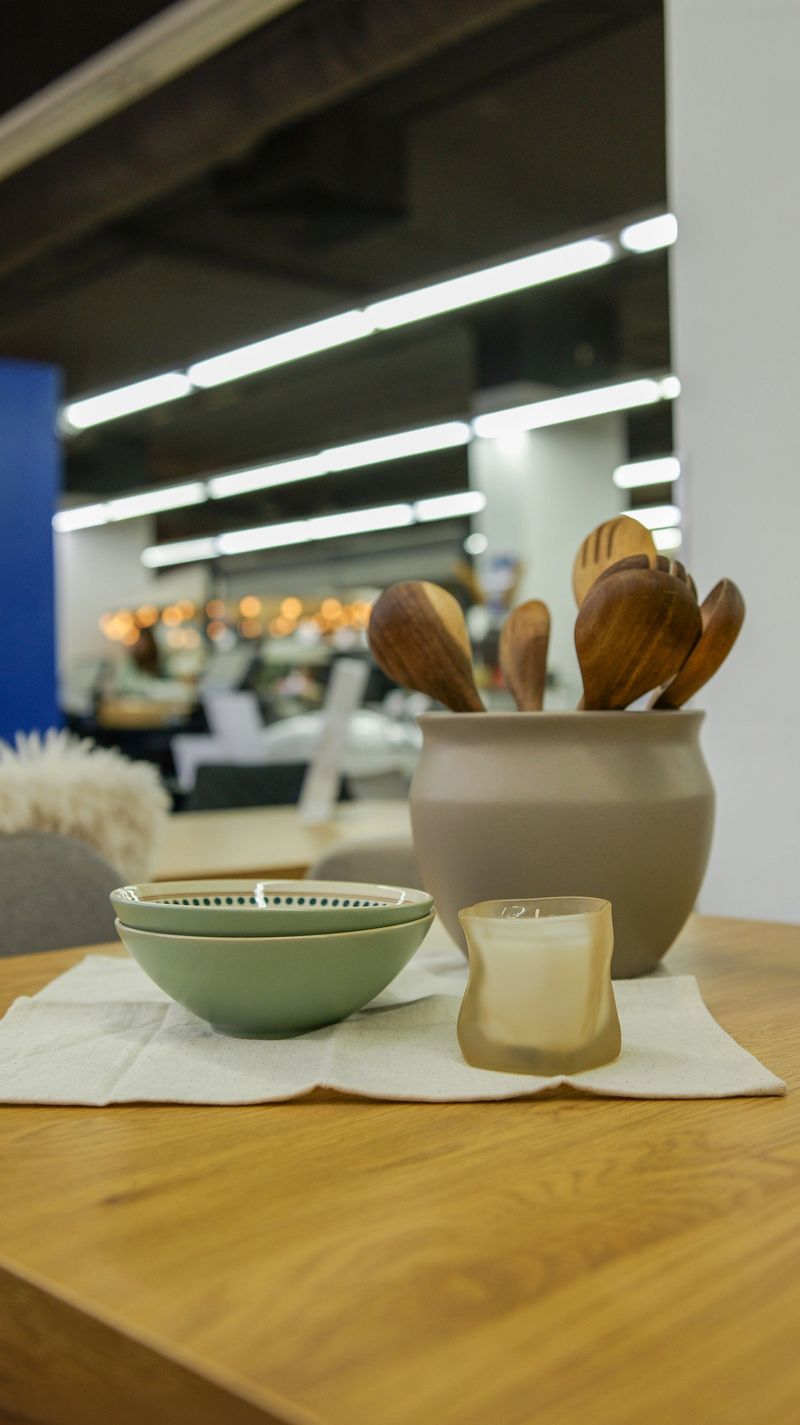 A collection of wooden spoons and bowls are displayed on a table, complemented by a lit candle creating a warm and inviting atmosphere