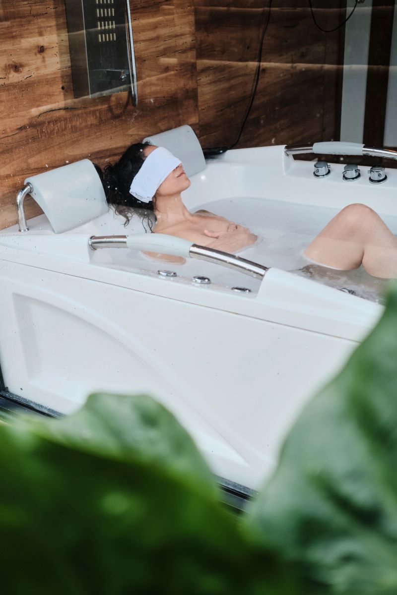 Woman immersing in a hot tub, wearing an eye towel for deep relaxation and self-care during a wellness treatment