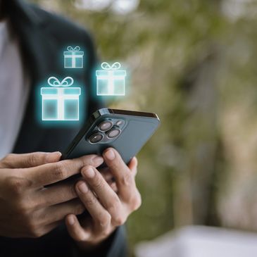 Person holding smartphone with gift icons floating above it.
