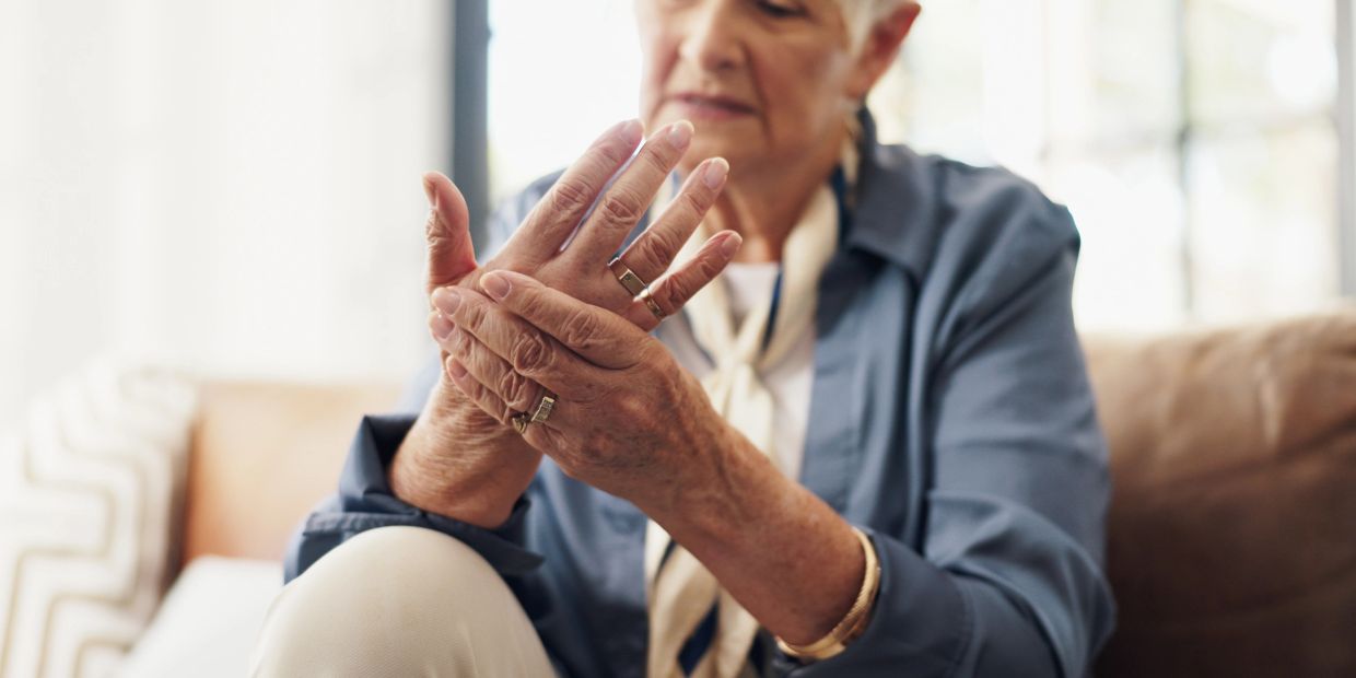 Elderly woman holding her painful hand, possibly from arthritis.
