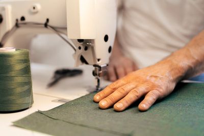 Hand guiding fabric under a sewing machine needle.
