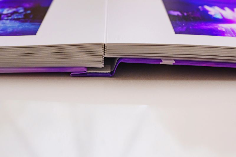 This close view shows the layout of a thick photo book with plastic pages. The texture of the photo paper is clear, emphasizing details of the pages.