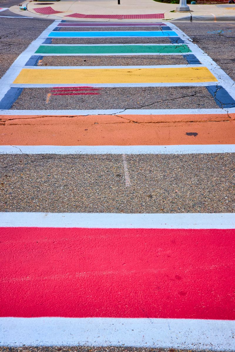 Vibrant rainbow crosswalk in downtown Kalamazoo, Michigan, symbolizes diversity and inclusivity. This colorful urban street feature highlights community spirit and public art in a bright daytime cityscape.